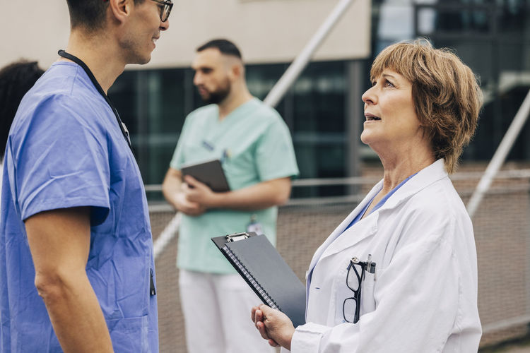 Side view of male colleague discussing with female physician