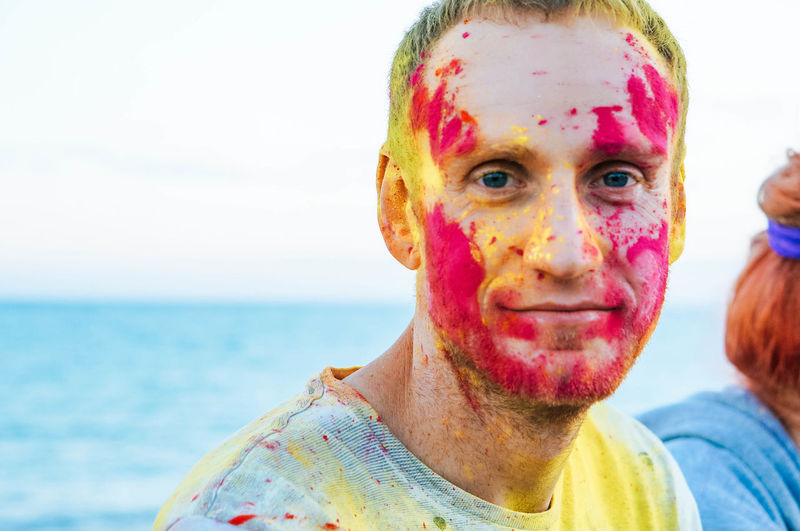 Close-up portrait of man with powder paint on face by sea