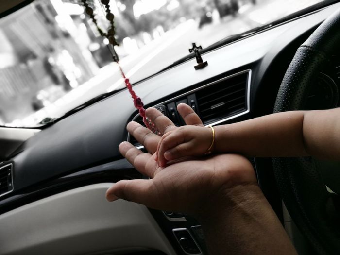 Cropped hand of father and child in car