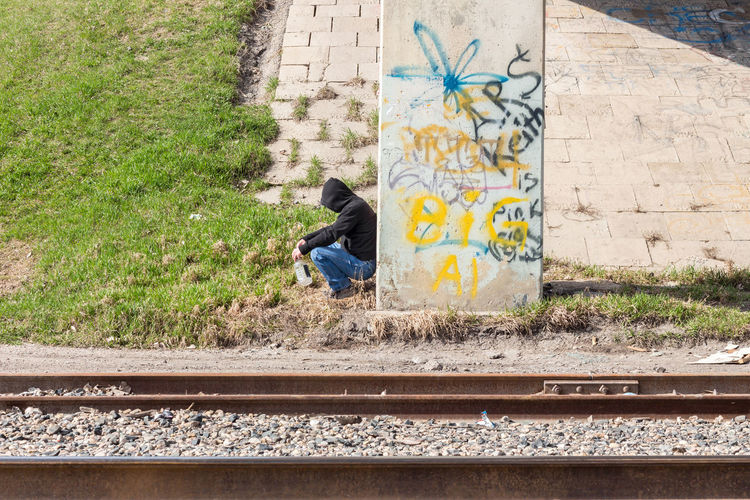 Rear view of man on railroad tracks against wall