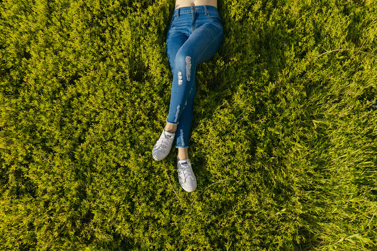 Low section of woman lying on grass field