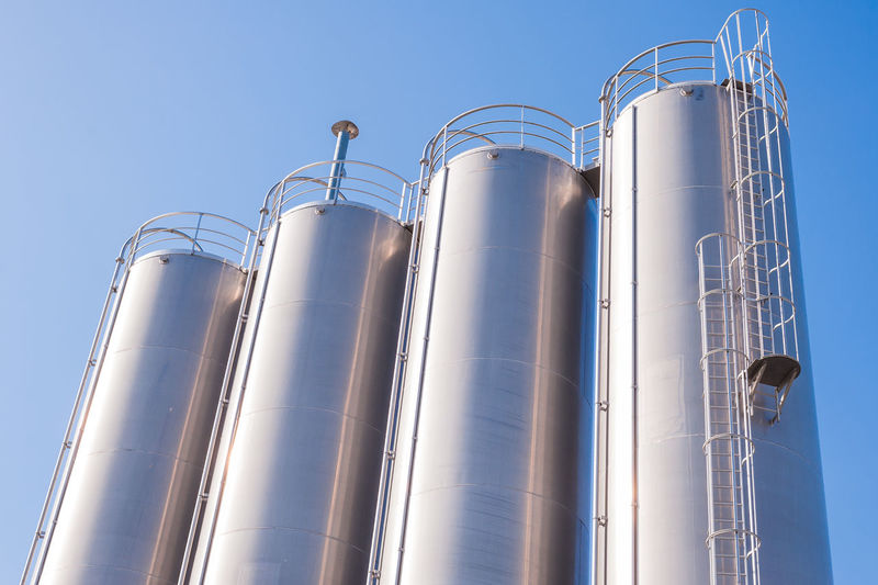 Silos in factory against sky