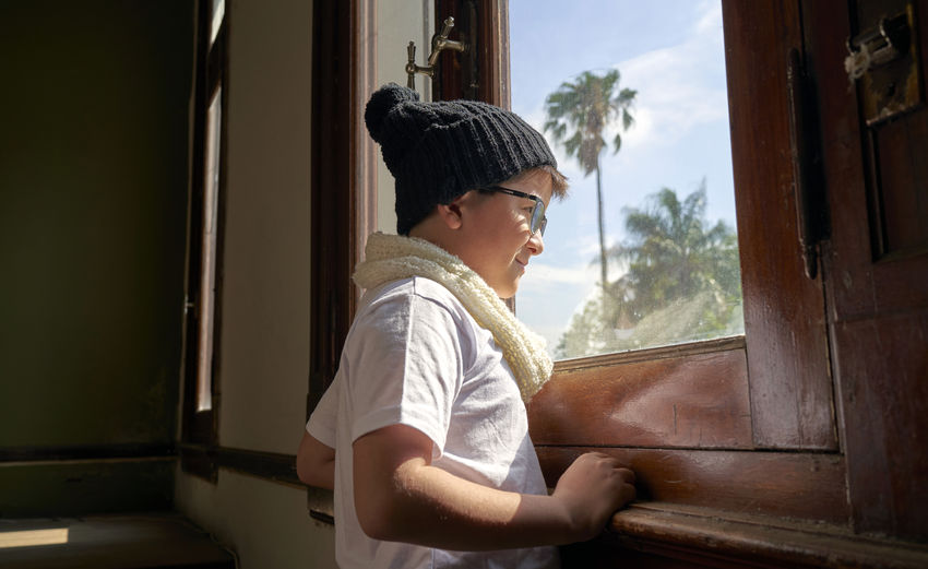 Child looks in the window sunny day
