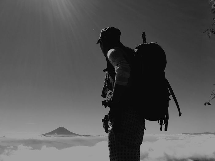 Hiker with backpack standing against sky