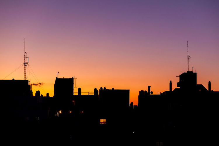 Silhouette buildings against clear sky at sunset