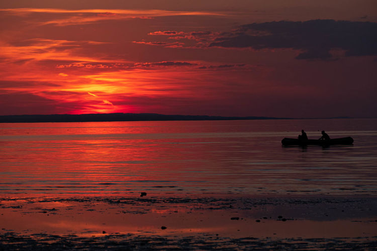 Silhouette canoeists at the lake of constance against sky during sunset
