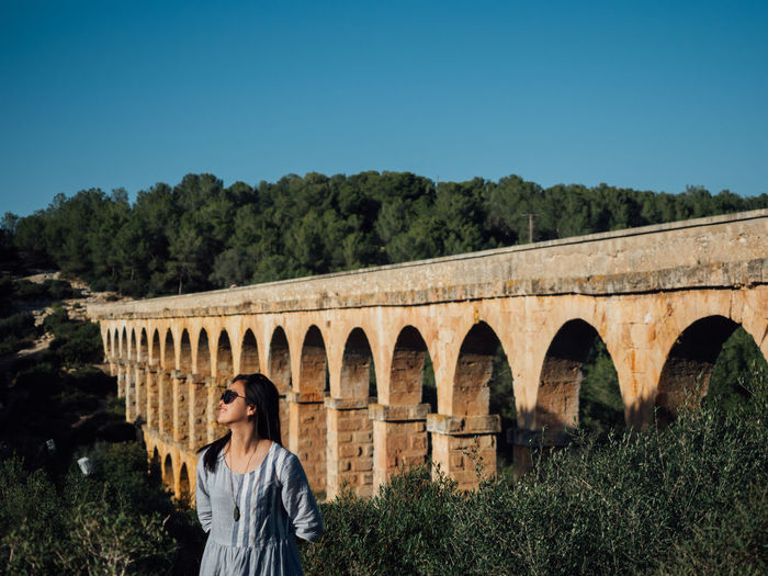 Woman standing against arch bridge