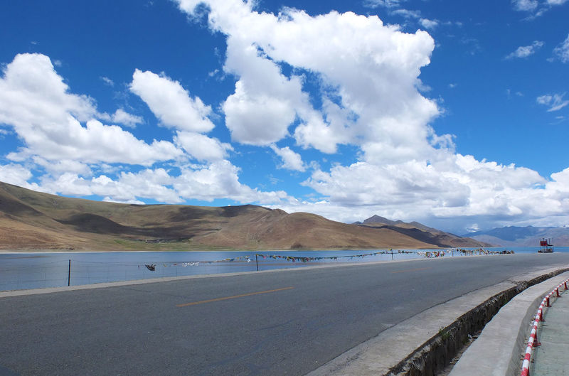 Scenic view of road against cloudy sky in tibet