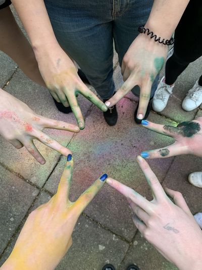 High angle view of people hands covered in colorful powder making star 