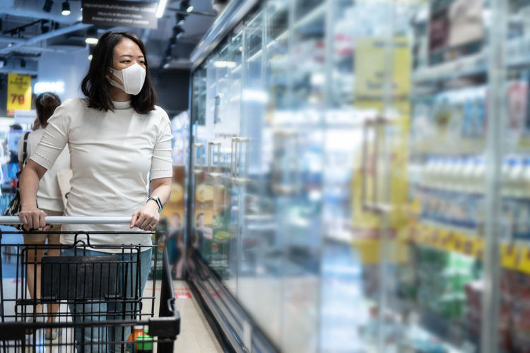 Young asian woman kid with face mask in supermarket. concept for life in outbreak and new normal.