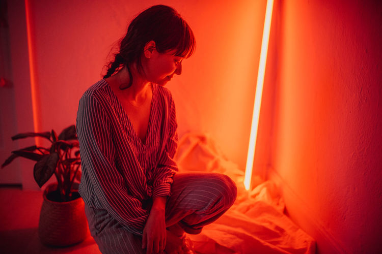 Smiling woman crouching in illuminated room