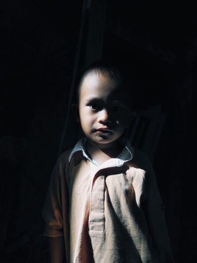Portrait of boy standing in darkroom