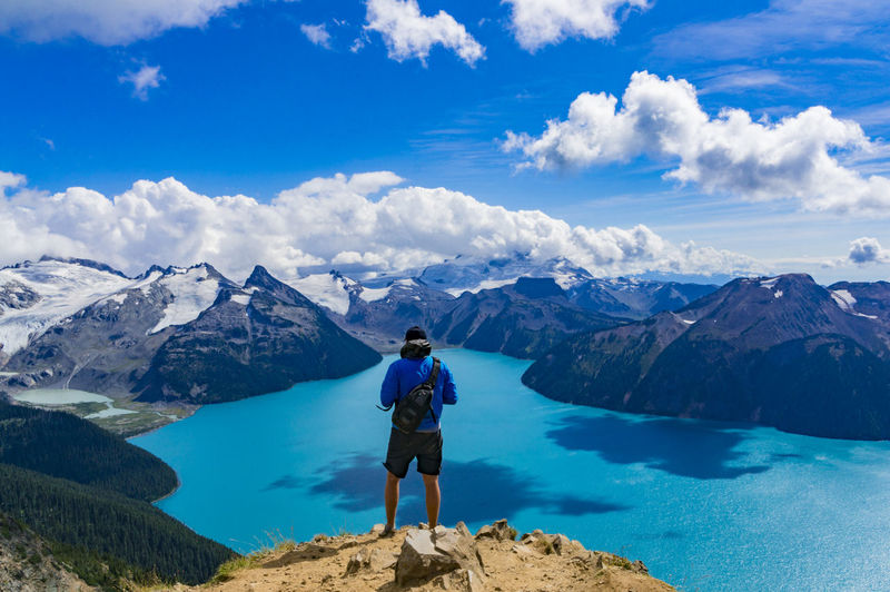 Rear view of man standing on panorama ridge overlooking garibaldi lake in garibaldi provincial park
