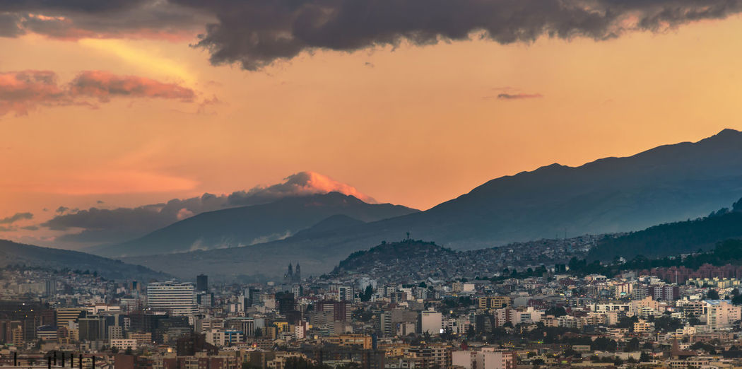 High angle view of cityscape by mountains against sky during sunset