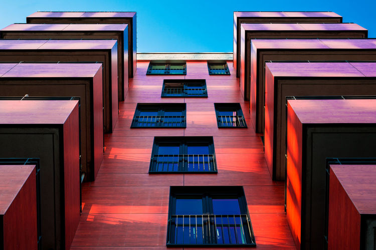 Low angle view of a red modern building against clear blue sky