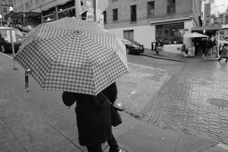 Rear view of woman walking on street during rainy season