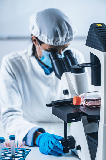 Scientist analyzing cultured artificial meat sample under the microscope in laboratory