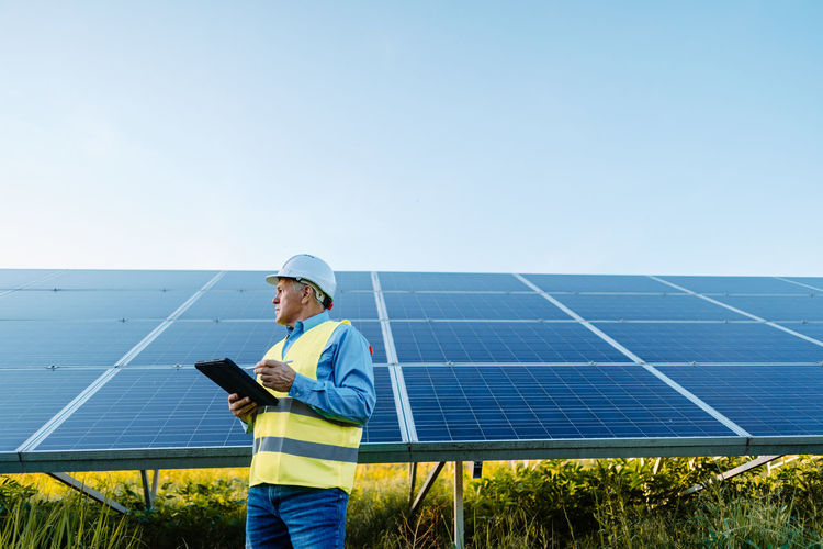 Senior male engineer with digital tablet contemplating in solar field