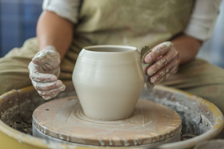 Midsection of woman making pottery in workshop