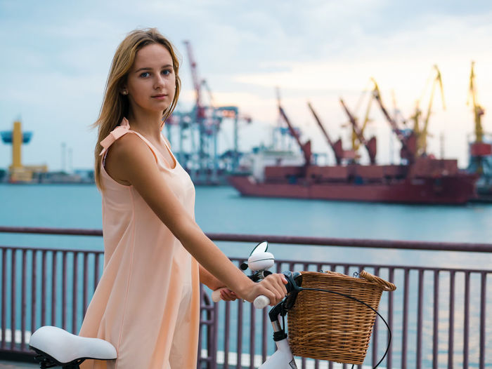 Portrait of beautiful woman with bicycle at harbor