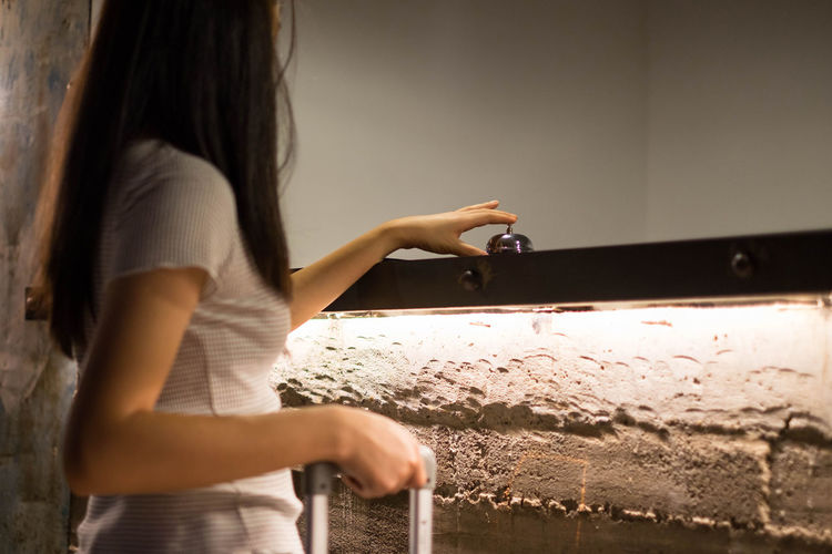 Woman pressing bell while standing by hotel reception