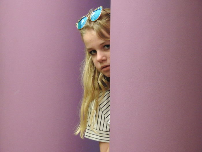 Portrait of girl hiding behind wall