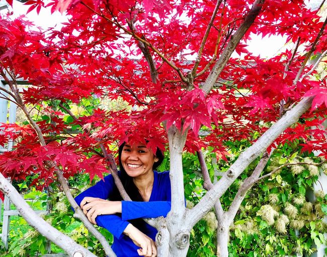 Portrait of smiling young woman by tree in park during autumn