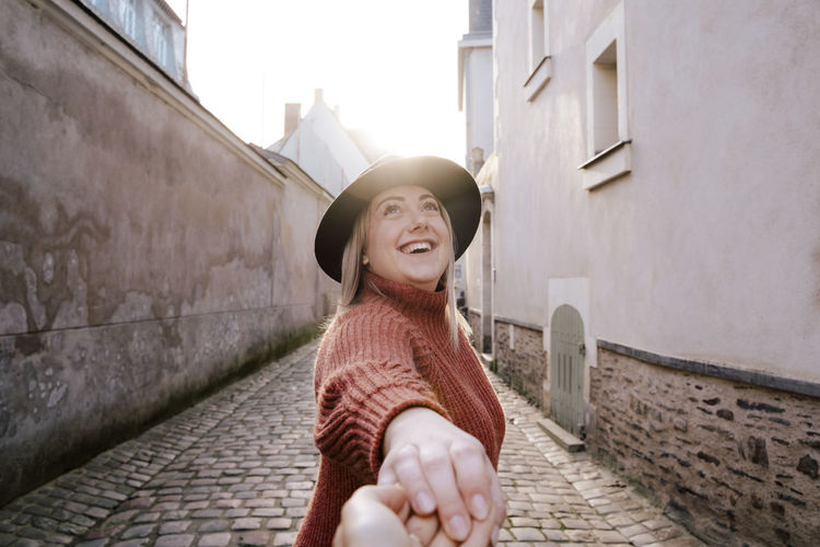 Smiling woman holding hand in alley