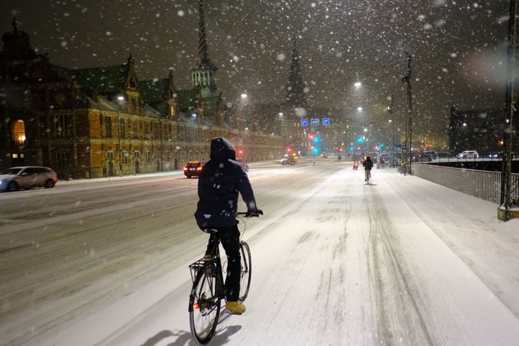 Rear view of man with bicycle on road in winter