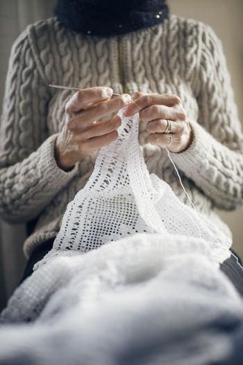 Midsection of woman knitting at home