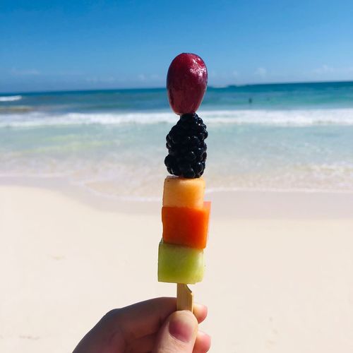Person holding ice cream cone on beach