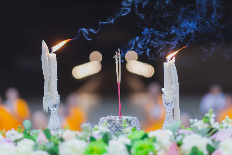 Close-up of lit candles and incense in temple