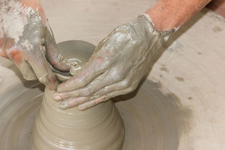 Cropped hands of man molding shape on pottery wheel