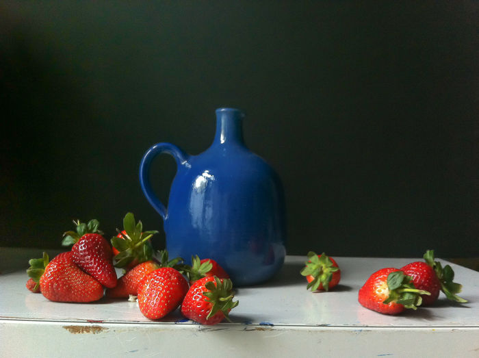 Strawberries in front of vase on table