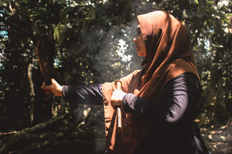 Side view of young woman in forest