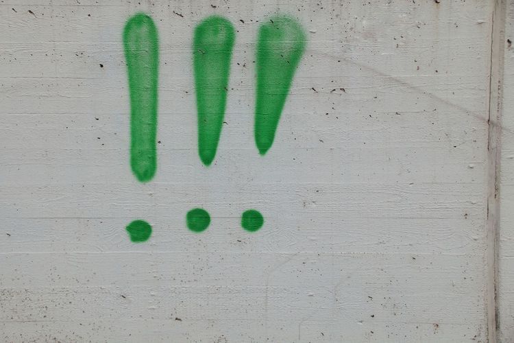 Close-up of exclamation points on white wall