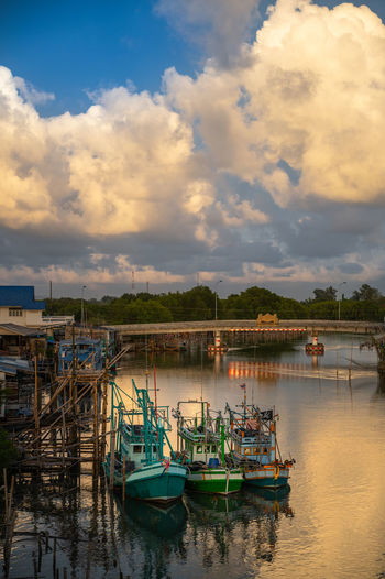 Fishing boats moored at harbor against sky during sunset