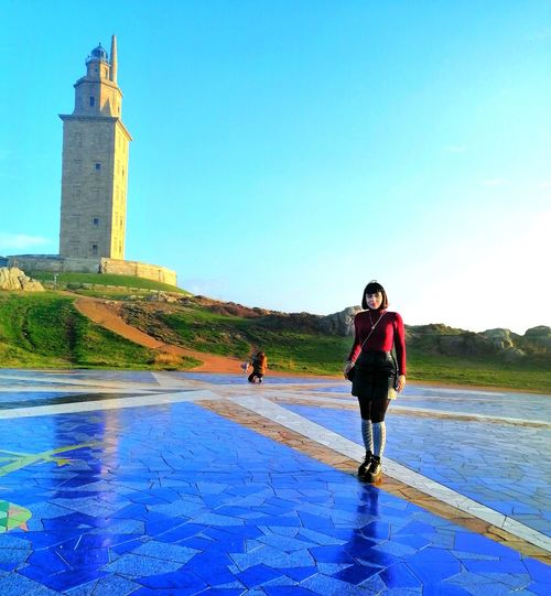Woman standing on pedestrian zone against lighthouse