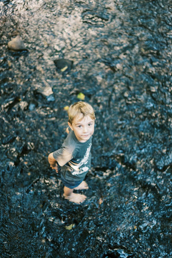 A five year old boy getting his feet wet in a river