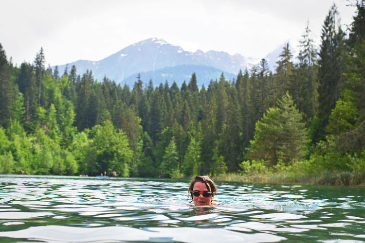 Young woman swimming in lake at forest