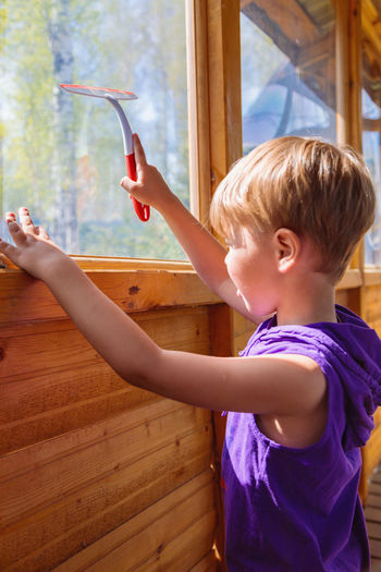 The child washes the windows with a special brush. a child with blond hair