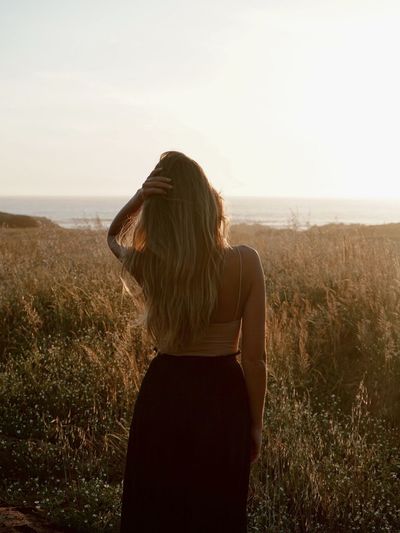 Rear view of woman standing on field against sky