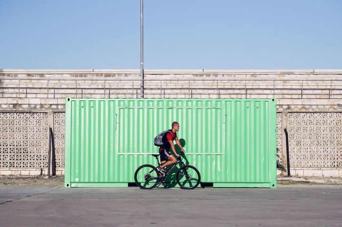 Side view of young man riding bicycle on wall