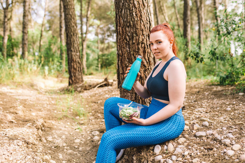 Side view of woman eating salad in forest