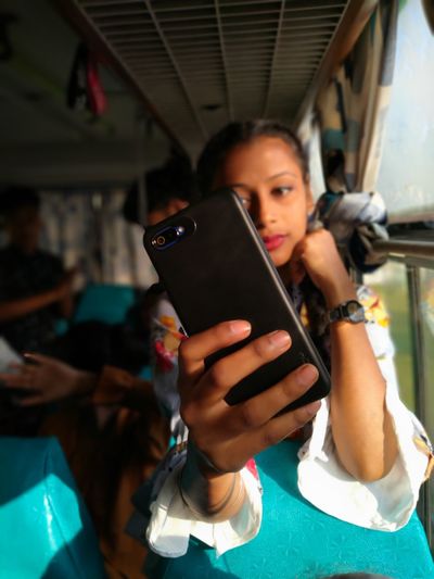 Teenager girl doing selfie while sitting in bus