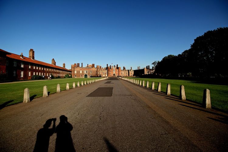 Shadow of people on road in front of hampton court palace