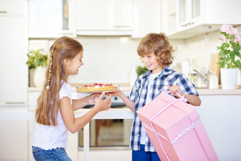 Siblings packing cake in gift box at home