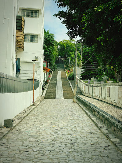 Empty footpath amidst buildings in city