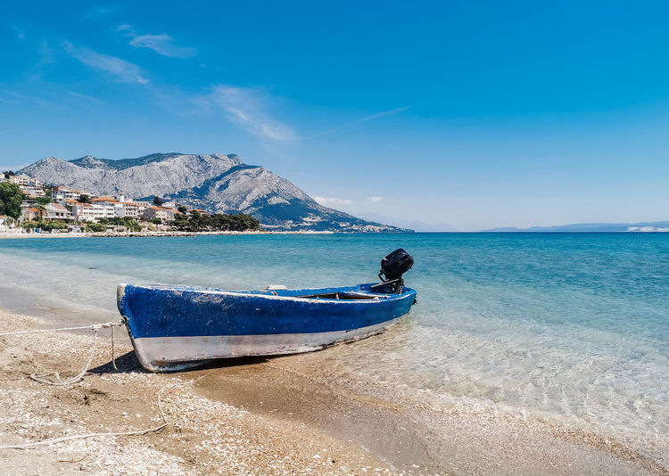 Old weathered boat on sandy beach on coast of adriatic sea near omiš in croatia.