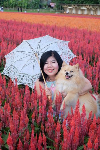 Portrait of smiling woman with dog against plants